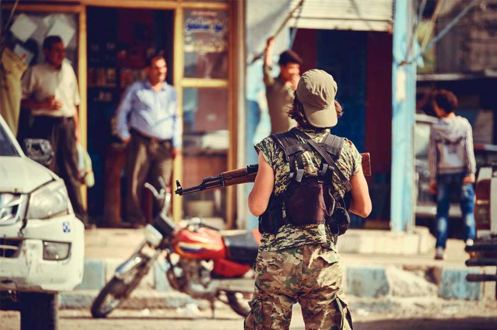 Soldatin mit Maschinengewehr vor einem Ladengeschäft